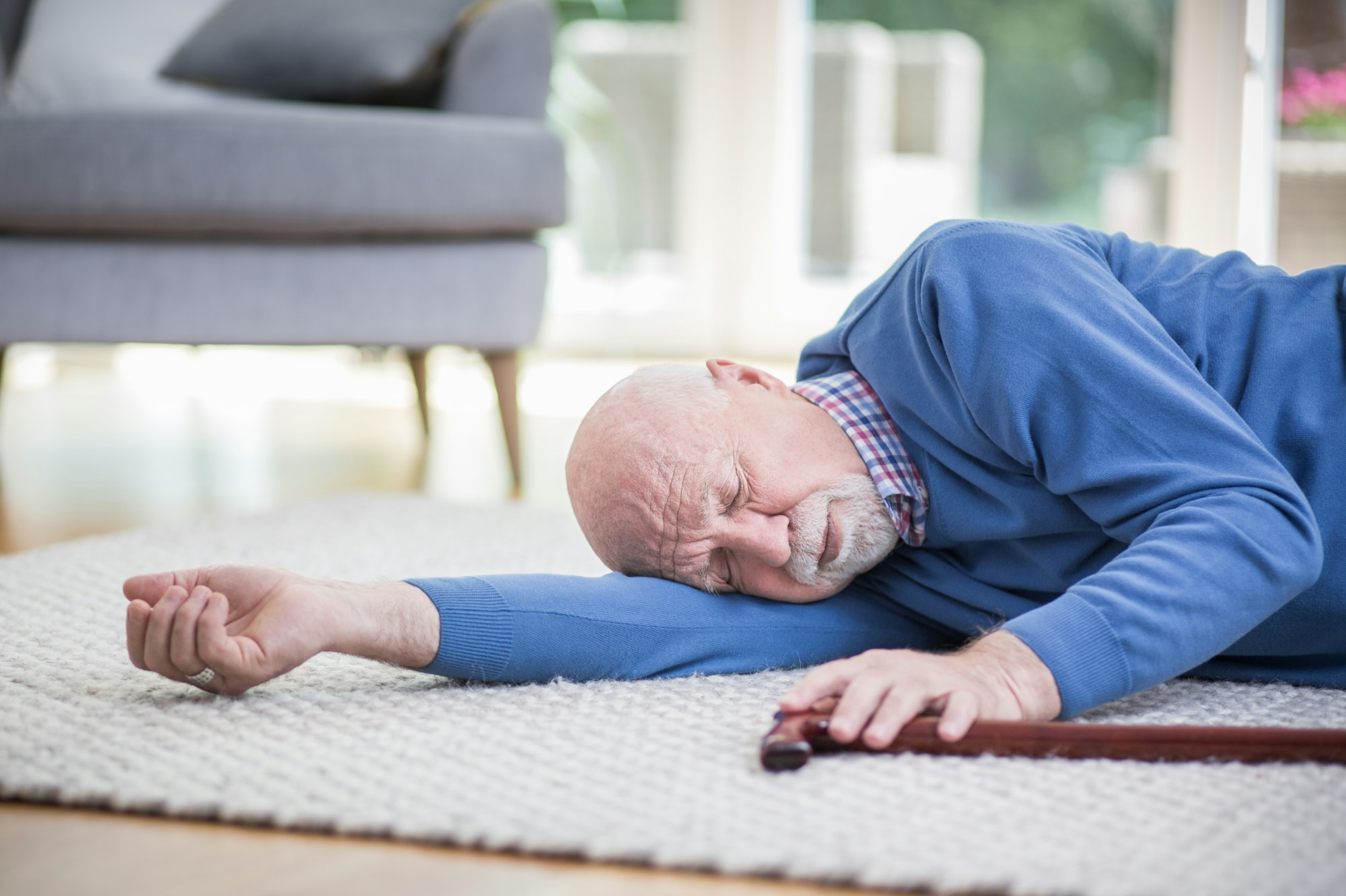 Senior man in blue sweater lying on the floor of his apartment